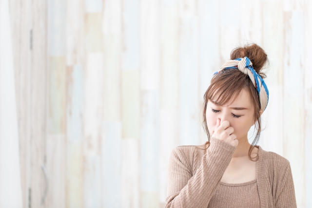 鼻をつまむ女性